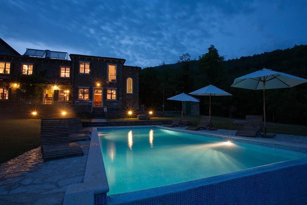 Villa Bazjaki illuminated beside its pool at dusk
